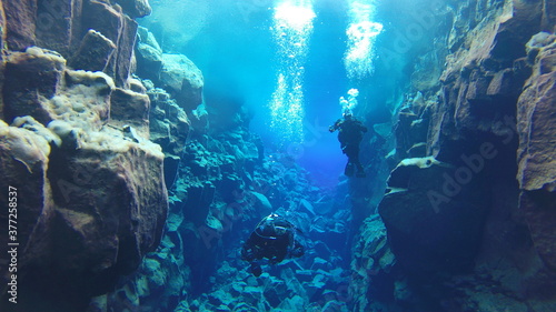 bubbles rising to reflective glacial water underwater surface whilst scuba diving in iceland