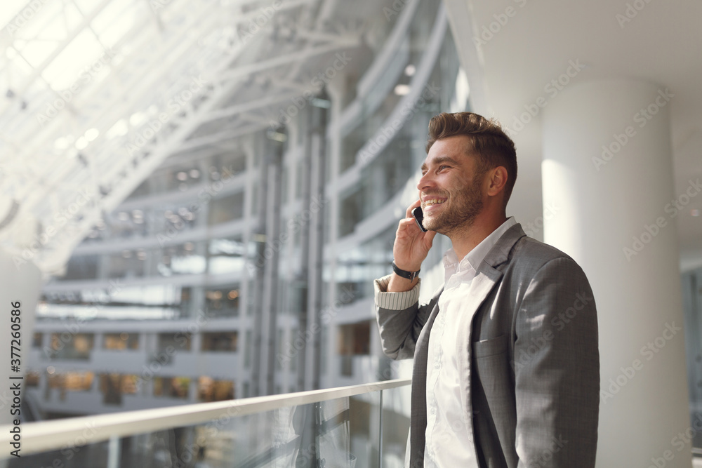 Handsome businessman in a suit and talking on the phone on the street. Portrait of a young man in business style smiling and laughing. Handsome businessman in a suit and talking on the phone on the street. Portrait of a young man in business style smiling and laughing.