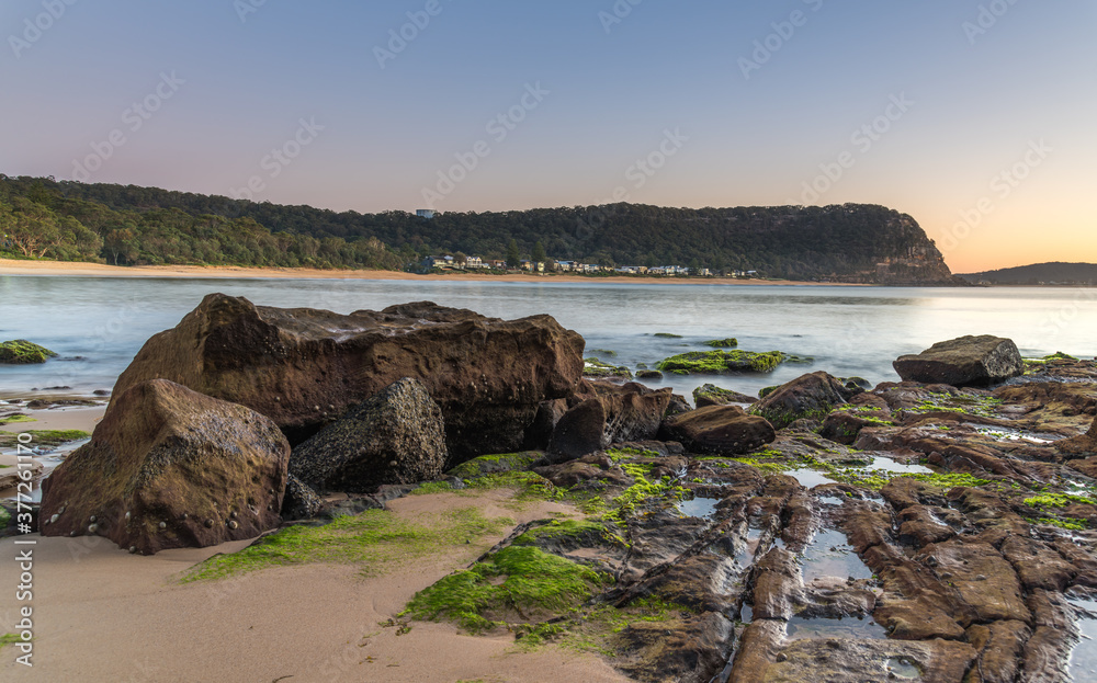 Sunrise with Clear Skies , Rocks and Green Moss at the Seaside