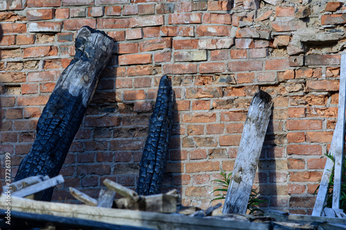 Charred sticks leaning against an old brick wall after a fire