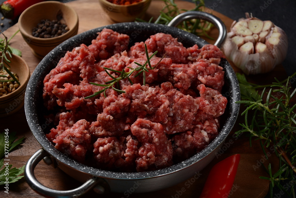 Minced beef. Ground meat with ingredients for cooking on black background