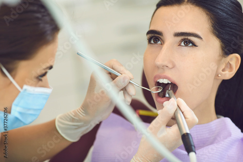 Dentist curing caries on woman patients tooth in clinic