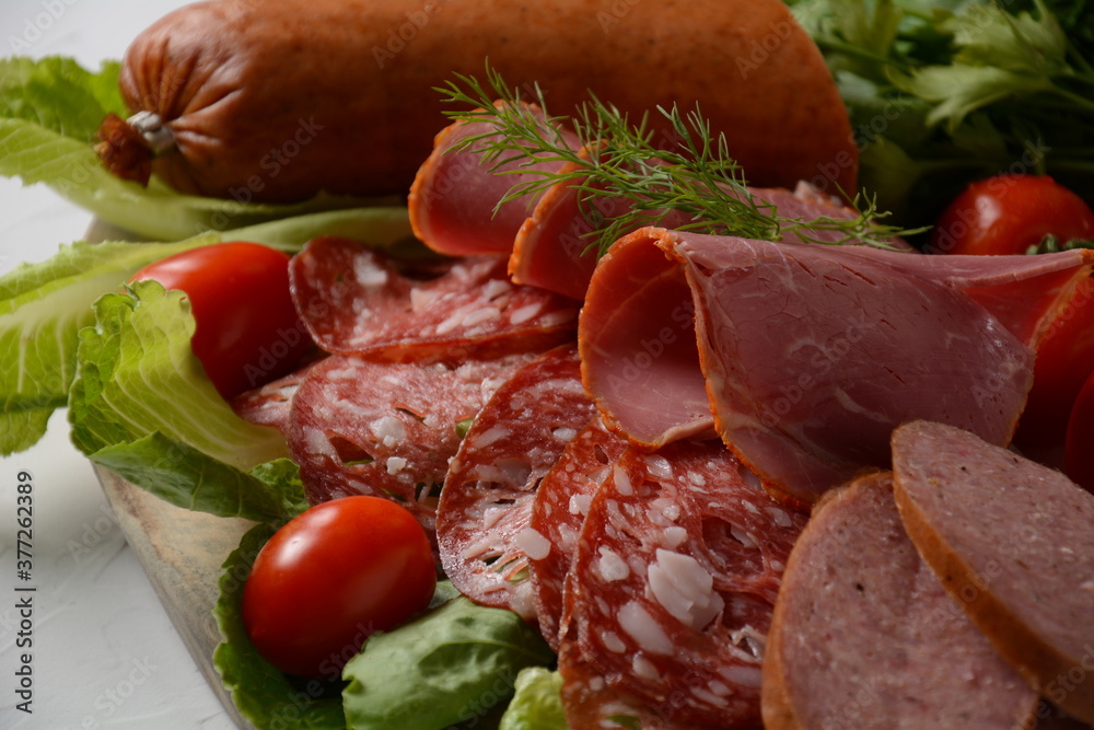 A selection of spicy dried or smoked  sausages on lettuce leaves with cherry tomatoes