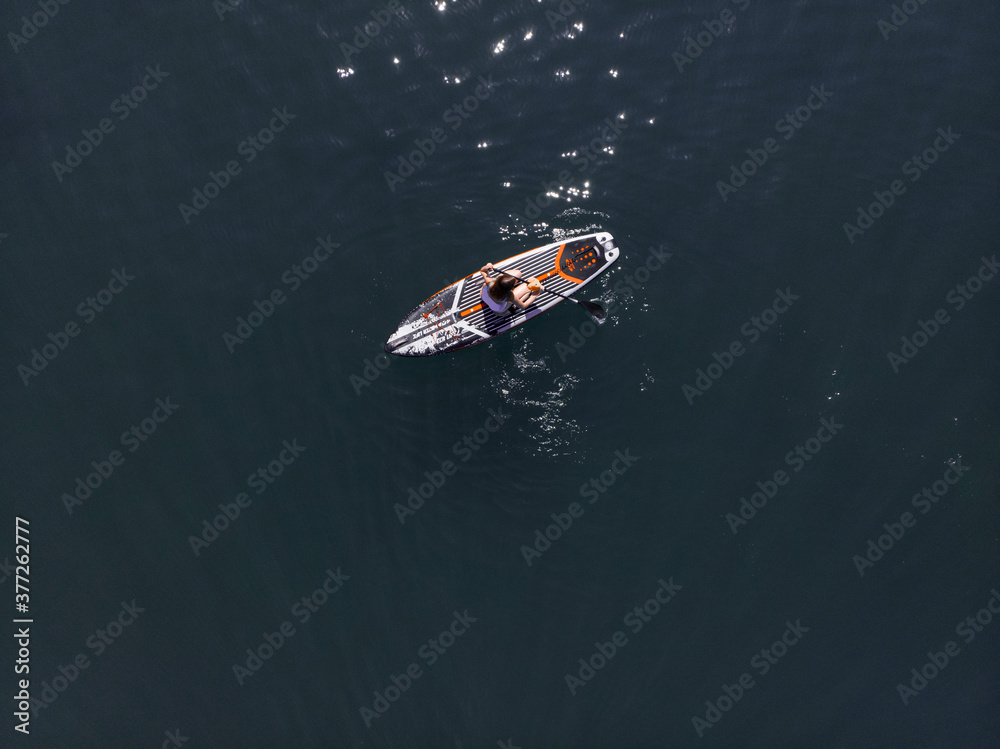 Fototapeta premium Attractive Woman on Stand Up Paddle Board, Woman paddling on sup board and enjoying turquoise transparent water. Tropical travel, wanderlust and water activity concept. Sunset and relax