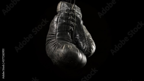 black vintage leather boxing glove hanging on a drawstring, black background