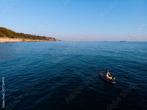 Attractive Woman on Stand Up Paddle Board, Woman paddling on sup board and enjoying turquoise transparent water. Tropical travel, wanderlust and water activity concept. Sunset and relax
