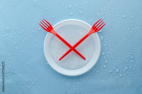 Top view of plastic dish and forks on the wet blue surface.Concept of Time to Stop Environmenal Pollution