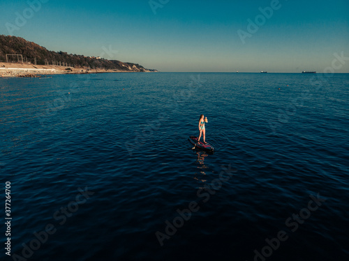 Attractive Woman on Stand Up Paddle Board  Woman paddling on sup board and enjoying turquoise transparent water. Tropical travel  wanderlust and water activity concept. Sunset and relax