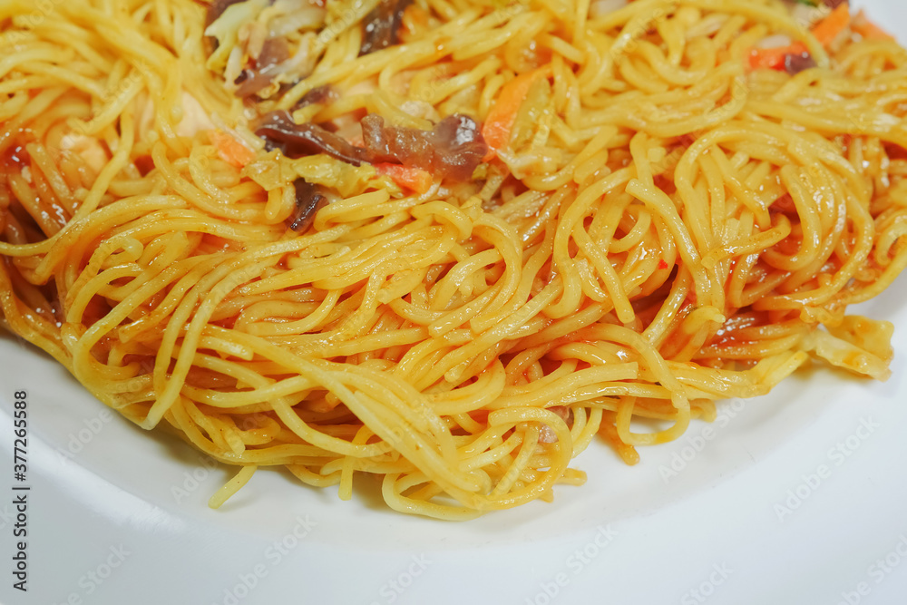 Simple chicken chow mein meal on a white plate and on a wooden table. Chinese stye tasty noodels with sauce and vegitables. Concept dinner, Asian flafour. Simple chicken chow mein meal on a white plate and on a wooden table. Chinese stye tasty noodels with sauce and vegitables. Concept dinner, Asian flafour.