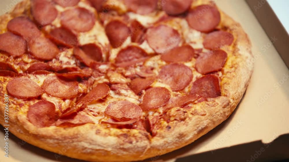 Spinning pizza with salami on carton boxes on grey background Spinning pizza with salami on carton boxes on grey background