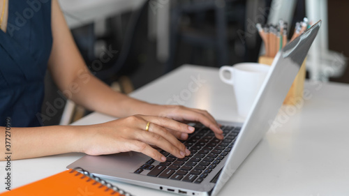 Female typing on laptop computer while working on her project in office room