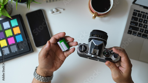 Male photographer holding camera and camera film on his hand in workspace