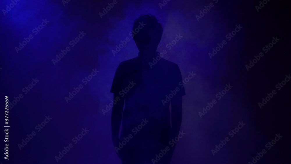 青いライトの中に立つ男性