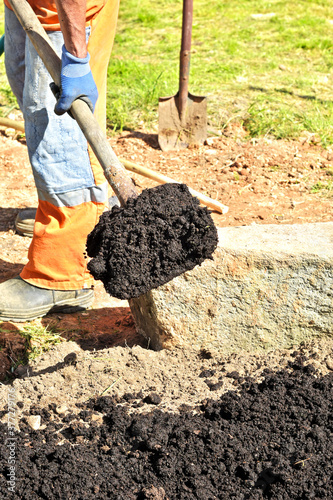 Man farmer digs the soil with a shovel in a private garden  workers loosen the black mud on the farm  the concept of agriculture autumn detail. A man with a shovel is preparing to dig.