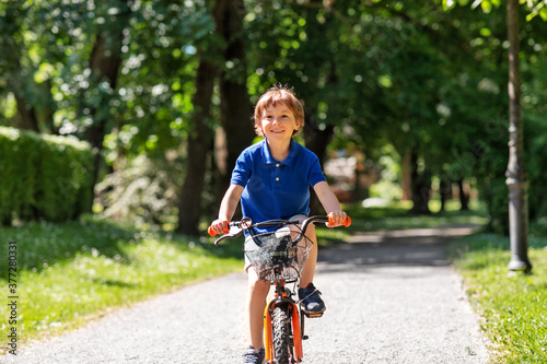 Fototapeta Naklejka Na Ścianę i Meble -  childhood, leisure and people - happy smiling little boy riding bicycle at summer park