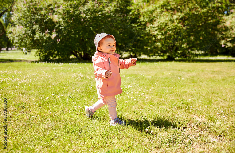 childhood, leisure and people concept - happy little baby girl in pink clothes walking at park in summer childhood, leisure and people concept - happy little baby girl in pink clothes walking at park in summer