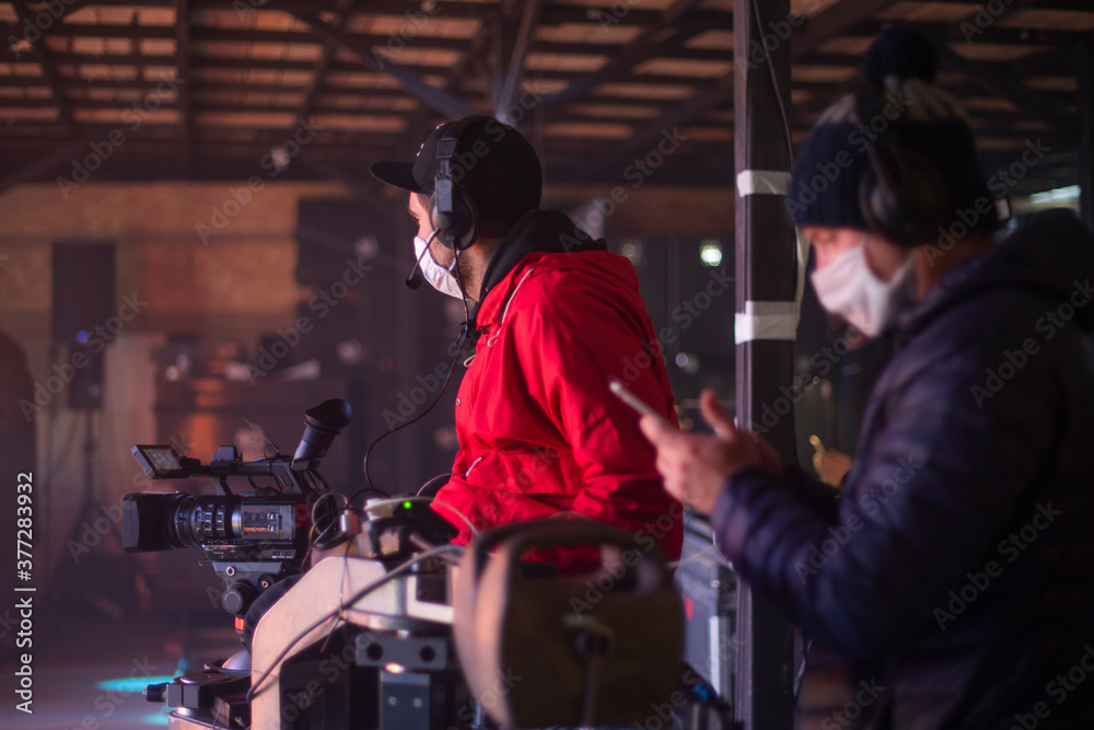 masked cameraman is filming a television show in the studio.