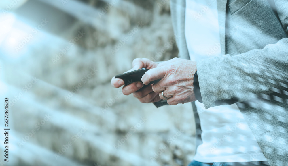 Man standing against a wall and using mobile phone; light effect