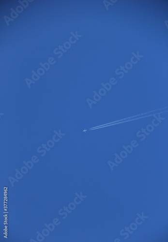 飛行機雲を描きながら青空を飛ぶ飛行機