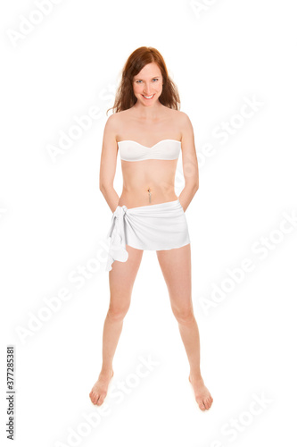 Cheerful young woman wearing a bath towel and a bandeau bra in front of white studio background © Jochen Schönfeld
