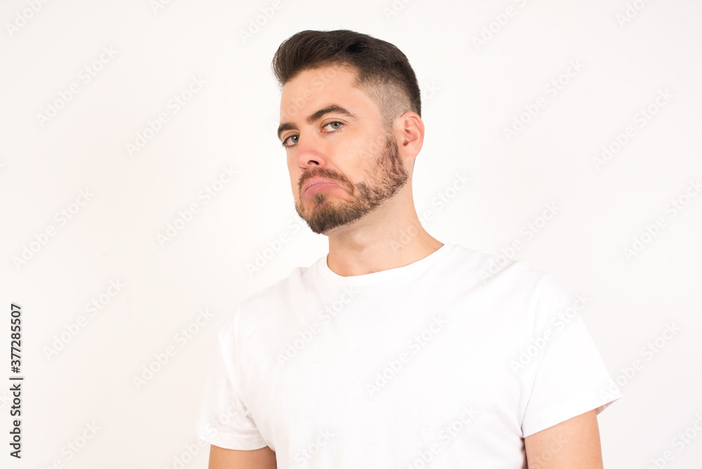 Beautiful man with snobbish expression curving lips and raising eyebrows, looking with doubtful and skeptical expression, suspect and doubt. Standing indoors over gray background. Beautiful man with snobbish expression curving lips and raising eyebrows, looking with doubtful and skeptical expression, suspect and doubt. Standing indoors over gray background.