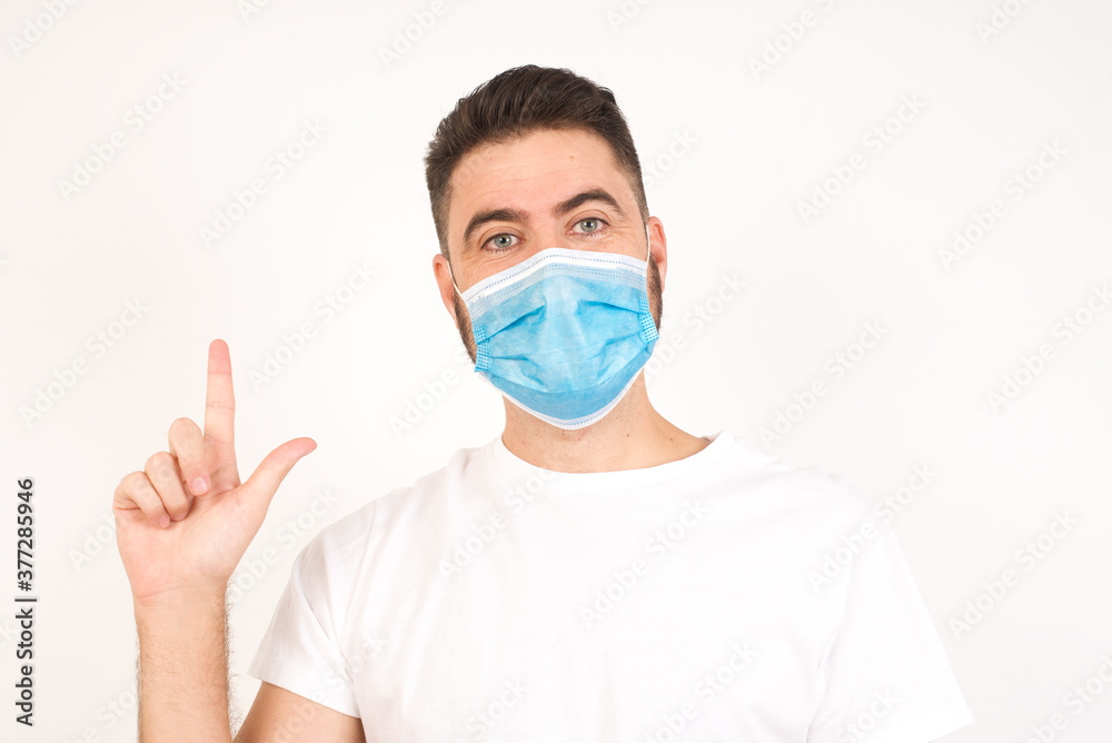 Close up portrait of pleasant looking blue eyed young man model has clever expression, raises one finger, remembers himself not to forget tell important thing.