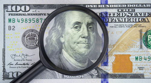 Magnifying glass on one hundred dollar bill, business concept photo