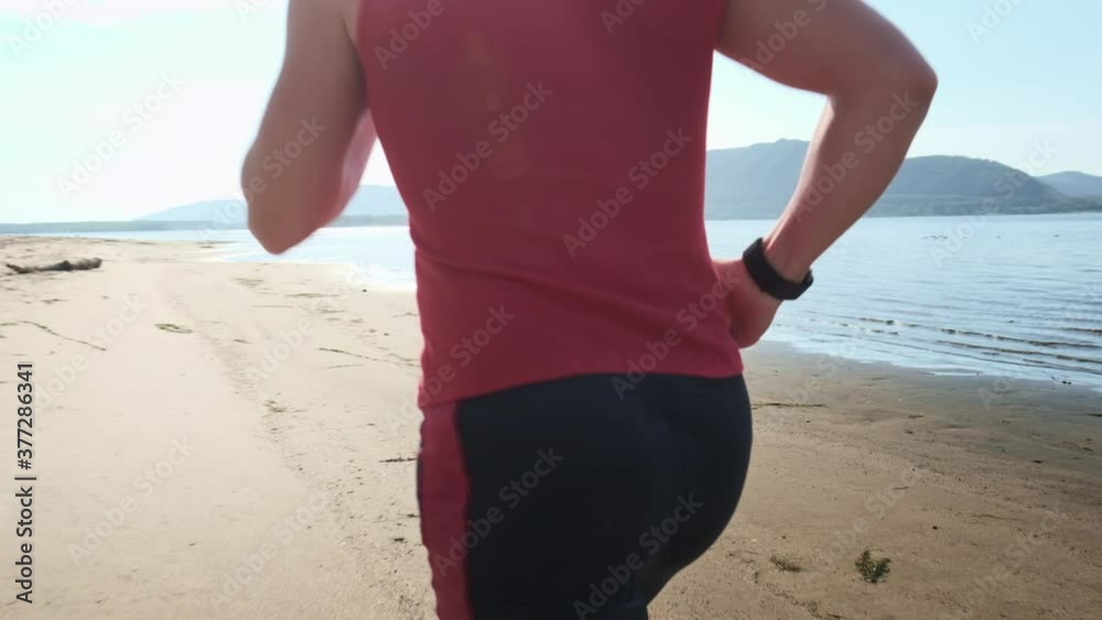 Man runs on a beach. Young sportive man runs barefoot on a sandy coast along the river