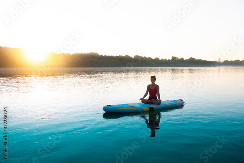 Woman meditating and practising yoga during sunrise © Marko