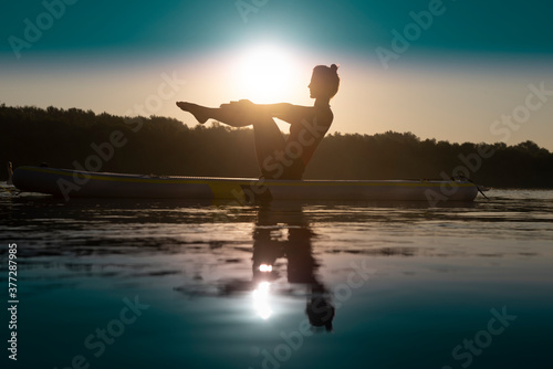 Woman meditating and practising yoga during sunrise