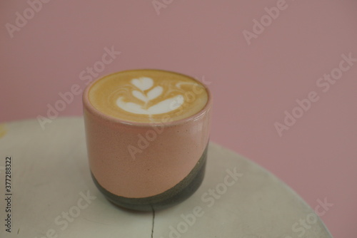 Close up of a hot cafe latte inside pink cup on a desk