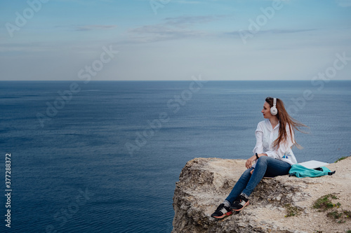 Young business woman working at the computer on the beach on the rock face.