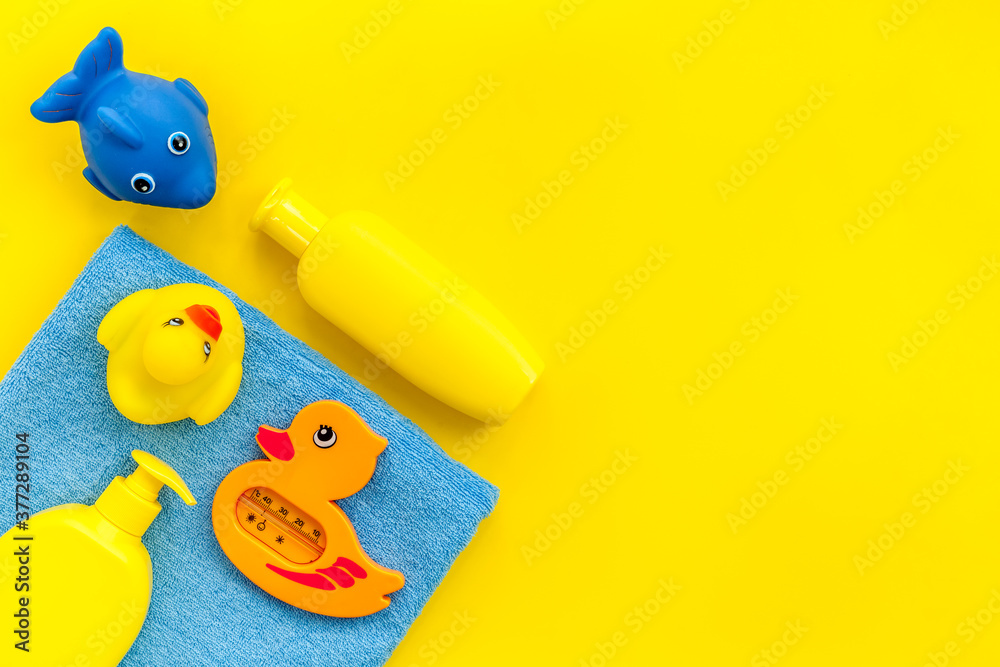 Bath accessories for kids. Yellow rubber duck,towel, cream, shampoo on Yellow  background top view