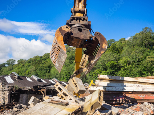 Hydraulic Excavator grab arm moving a demolished wall