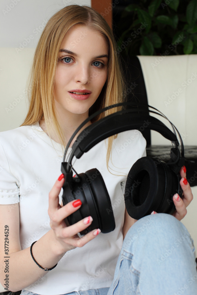 Fototapeta premium A young woman holds a pair wireless headphones in her hand.