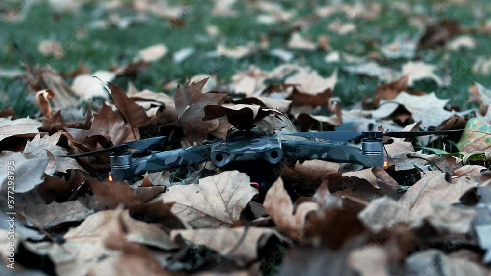 Drone in camouflage livery takes off from an autumn meadow Drone in camouflage livery takes off from an autumn meadow