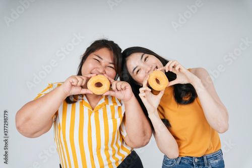 Two asian woman holding donut over white background.