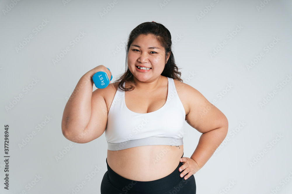 Asian chubby woman in white sport bra exercise with blue dumbbell. Asian chubby woman in white sport bra exercise with blue dumbbell.