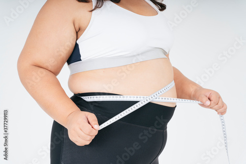Healthy asian chubby woman in white sportbra and measuring tape.