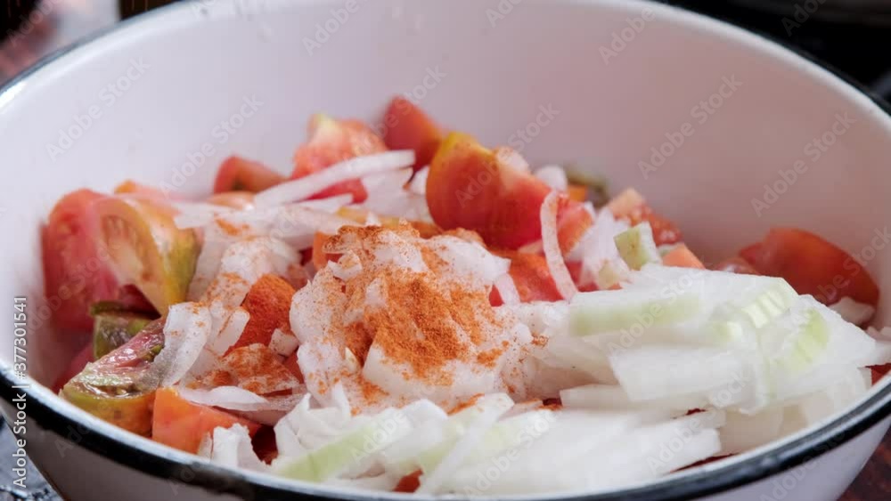 Adding spices and salt to the fresh tomato salad. Close-up. Adding spices and salt to the fresh tomato salad. Close-up.
