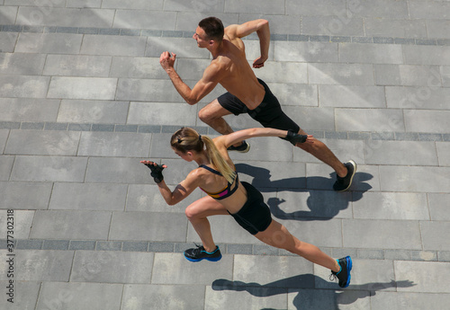 Strong. Young couple in sports outfit doing morning workout outdoors. Man and woman doing cardio and strenght exercises, practicing activity for lower and upper body. Sport, healthy lifestyle concept.