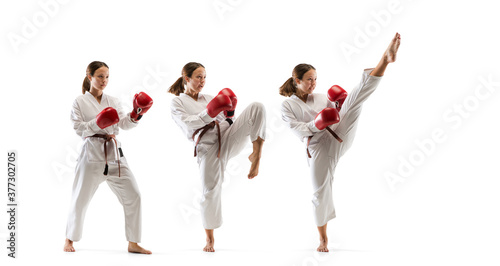 High. Junior in kimono practicing taekwondo combat, martial arts. Young female fighter with red gloves training on white studio background in motion, dymanic. Concept of healthy lifestyle, action.