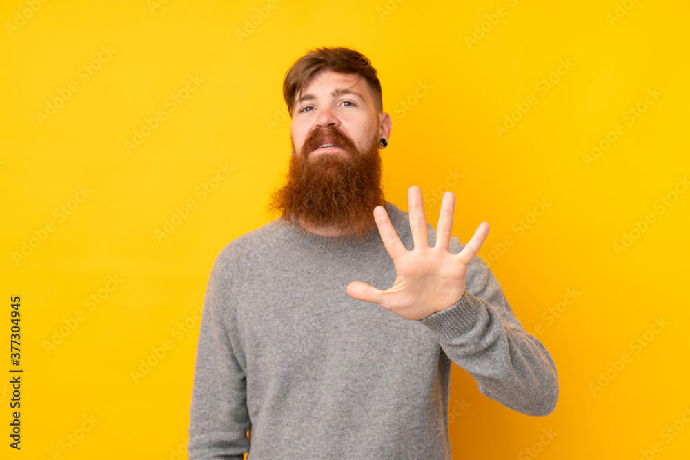Redhead man with long beard over isolated yellow background counting five with fingers Redhead man with long beard over isolated yellow background counting five with fingers