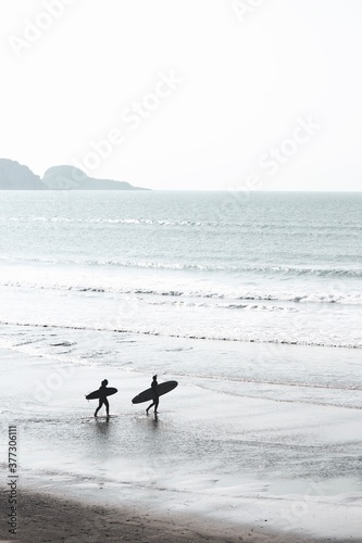 Photography Surfing Lifestyle at the beach with two longboard girls and the ocean behind the