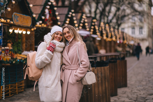 two girls stand at the christmas market decorated with christmas garlands