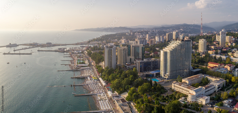 Blue black sea coast in Sochi with houses under the summer sky. Beach. Modern houses and hotels by the sea.