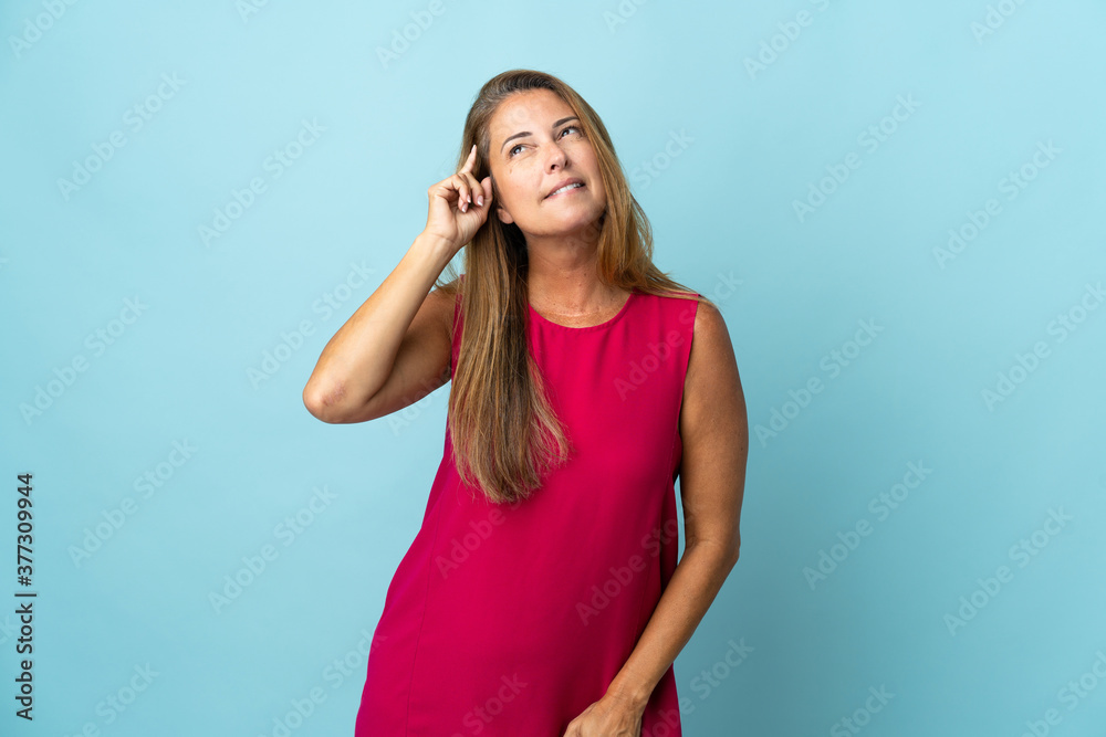 Middle age brazilian woman isolated on blue background having doubts and with confuse face expression Middle age brazilian woman isolated on blue background having doubts and with confuse face expression