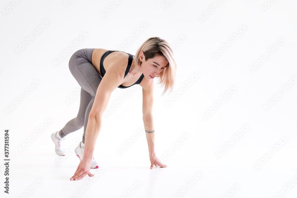 Healthy young woman preparing for a run. Fit female athlete ready for a spring over white background with copy space. Isolate Healthy young woman preparing for a run. Fit female athlete ready for a spring over white background with copy space. Isolate