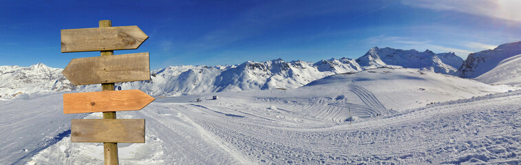 wooden sign in front of a beautiful snowy mountain landscape in winter under blue sky