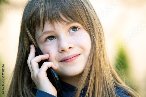 Portrait of pretty child girl with long hair talking on cell phone. Little female kid communicating using smartphone. Children communication concept.